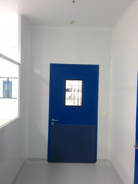 Cleanroom door and wall panel interface for pharmaceutical pressure and cleaning control